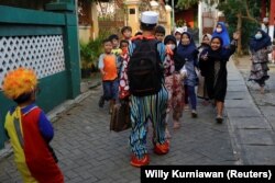 Hendrawan and his son are greeted by children as they arrive to teach. (REUTERS/Willy Kurniawan)