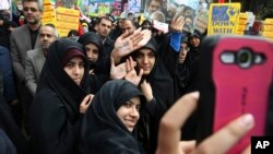 FILE - Iranian women demonstrators take a selfie while showing their hands with slogans against the U.S. and in support of Supreme Leader Ayatollah Ali Khamenei during an annual rally in front of the former U.S. Embassy in Tehran, Iran, Oct. 4, 2015.