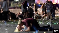 A man lays on top of a woman as others flee the Route 91 Harvest country music festival grounds after a active shooter was reported on Oct. 1, 2017 in Las Vegas, Nevada.