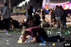 A man lays on top of a woman as others flee the Route 91 Harvest country music festival grounds after a active shooter was reported on Oct. 1, 2017 in Las Vegas, Nevada.