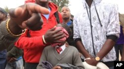 FILE: A father covers the face of his daughter with a wet towel after she was teargassed by armed Zimbabwean police in Harare, Monday, July, 4, 2016. (AP Photo/Tsvangirayi Mukwazhi)
