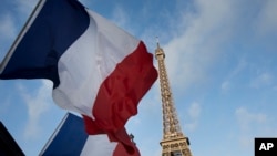 French flags fly as the closed Eiffel Tower is seen in the background on the first of three days of national mourning in Paris, Nov. 15, 2015. 