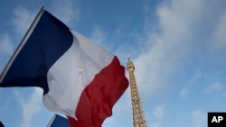 French flags fly as the closed Eiffel Tower is seen in the background on the first of three days of national mourning in Paris, Nov. 15, 2015. 