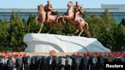 North Koreans bow to bronze statues of North Korea founder Kim Il-sung and late leader Kim Jong-il. (REUTERS/Kyodo)