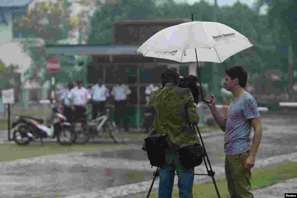 Seorang jurnalis mengambil gambar pintu masuk kompleks tempat rumah pilot Zaharie Ahmad Shah, kapten pesawat Malaysia Airlines penerbangan MH370, berada di Shah Alam, dekat Kuala Lumpur (16/3). (Reuters/Samsul Said)