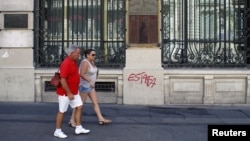 Tourists walk past Spain's former Banco Espanol de Credito in Madrid, August 28, 2012. 