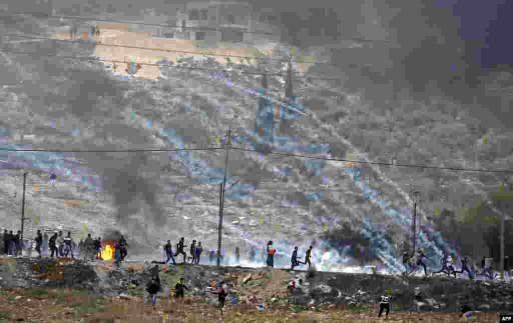 Palestinian protesters run for cover amidst smoke during clashes with Israeli security forces near the Huwara checkpoint south of Nablus in the Israeli-occupied West Bank.