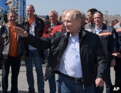 Russian President Vladimir Putin gestures while speaking to a group of workers after driving a truck to officially open the much-anticipated bridge linking Russia and the Crimean peninsula the opening ceremony near in Kerch, Crimea, May 15, 2018.