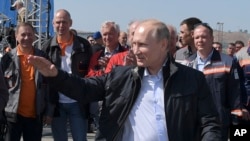 Russian President Vladimir Putin gestures while speaking to a group of workers after driving a truck to officially open the much-anticipated bridge linking Russia and the Crimean peninsula the opening ceremony near in Kerch, Crimea, Tuesday, May 15, 2018.
