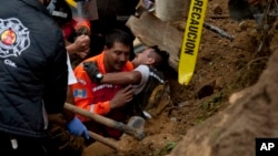 A fireman is rescued after he was trapped while working at the site of a landslide in Cambray, a neighborhood in the suburb of Santa Catarina Pinula, about 15 kilometers east of Guatemala City, Oct. 3, 2015. 