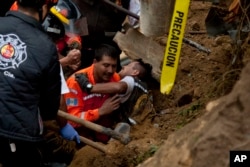 A fireman is rescued after he was trapped while working at the site of a landslide in Cambray, a neighborhood in the suburb of Santa Catarina Pinula, about 10 miles east of Guatemala City, Oct. 3, 2015.