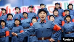 FILE - Retired female workers dressed as red army soldiers sing revolutionary songs.