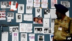 An Indian paramilitary soldier looks at the gate of an airport, covered with special announcements and pictures of missing people, in Jollygrant, India, June 26, 2013. 