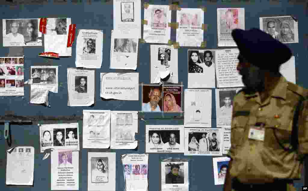 An Indian paramilitary soldier looks at the gate of an airport, covered with special announcements and pictures of missing people, in Jollygrant, India, June 26, 2013. 