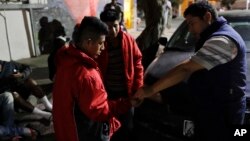 Migrant shelter director Jose Garcia, right, gives a few coins to two men from Guatemala on their way to cross into the United States in Tijuana, Mexico, Nov. 14, 2016.