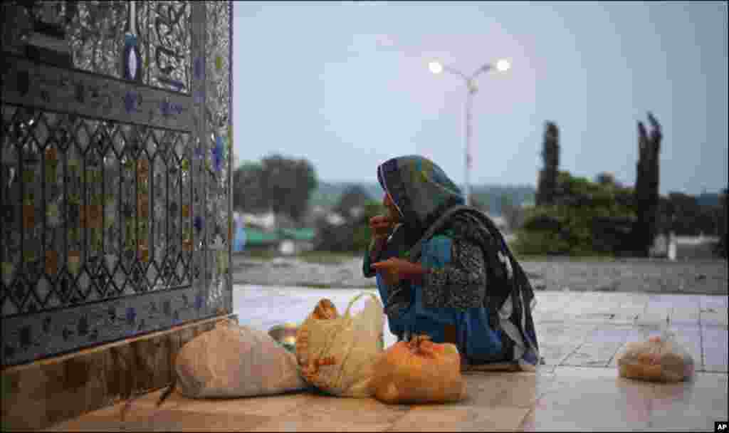 A woman breaks her fast with donated food at the Bari Imam Sufi shrine in Islamabad