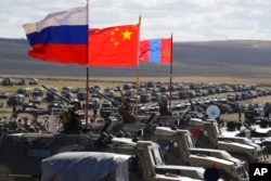FILE - Russian, Chinese and Mongolian national flags set on armored vehicles develop in the wind during a military exercises on training ground "Tsugol, south-east of the city of Chita during the military exercises Vostok 2018 in Eastern Siberia, Russia,