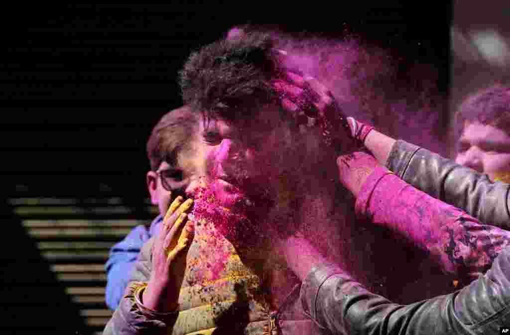 Indians put colored powder on each other as they celebrate Holi in Jammu.