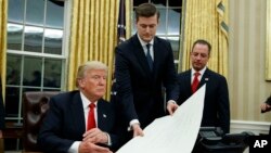 FILE - Then-White House Chief of Staff Reince Priebus, right, watches as White House Staff Secretary Rob Porter, center, hands President Donald Trump a confirmation order in the Oval Office of the White House, in Washington, Jan. 20, 2017.