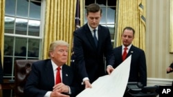 Le secrétaire du personnel de la Maison Blanche, Rob Porter, au centre, remet un document au président Donald Trump, à gauche, dans le bureau ovale de la Maison-Blanche, Washington, 20 janvier 2018.