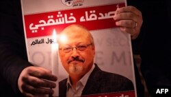 A demonstrator holds a poster picturing Saudi journalist Jamal Khashoggi and a lightened candle during a gathering outside the Saudi Arabia consulate in Istanbul, on October 25, 2018.