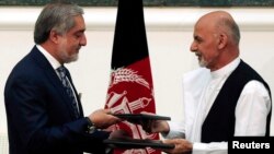 Kandidat-kandidat presiden Afghanistan Ashraf Ghani (kanan) dan Abdullah Abdullah menandatangani kesepakatan mengenai pembagian pemerintahan persatuan di Kabul (21/9). (Reuters/Omar Sobhani)