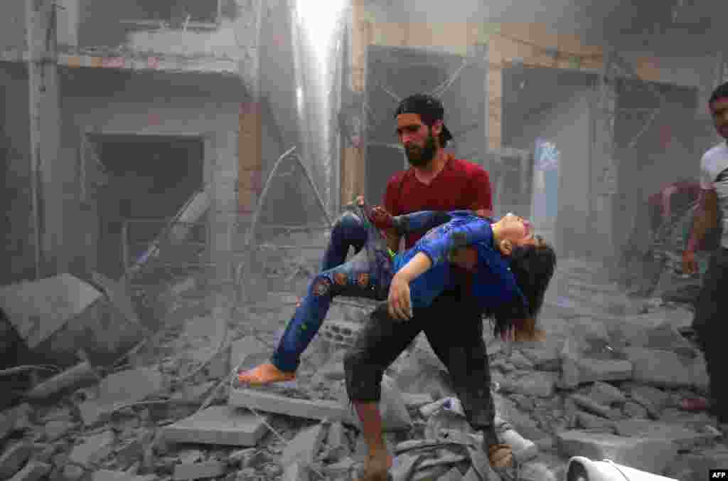 A man evacuates a young girl after a reported airstrike by government forces and their allies in the jihadist-held Syrian town of Maaret Al-Noman in the southern Idlib province.