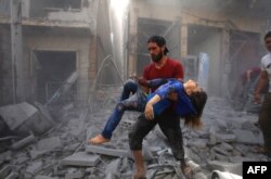 A man evacuates a young bombing casualty after a reported air strike by regime forces and their allies in the jihadist-held Syrian town of Maaret Al-Noman in the southern Idlib province, May 26, 2019.