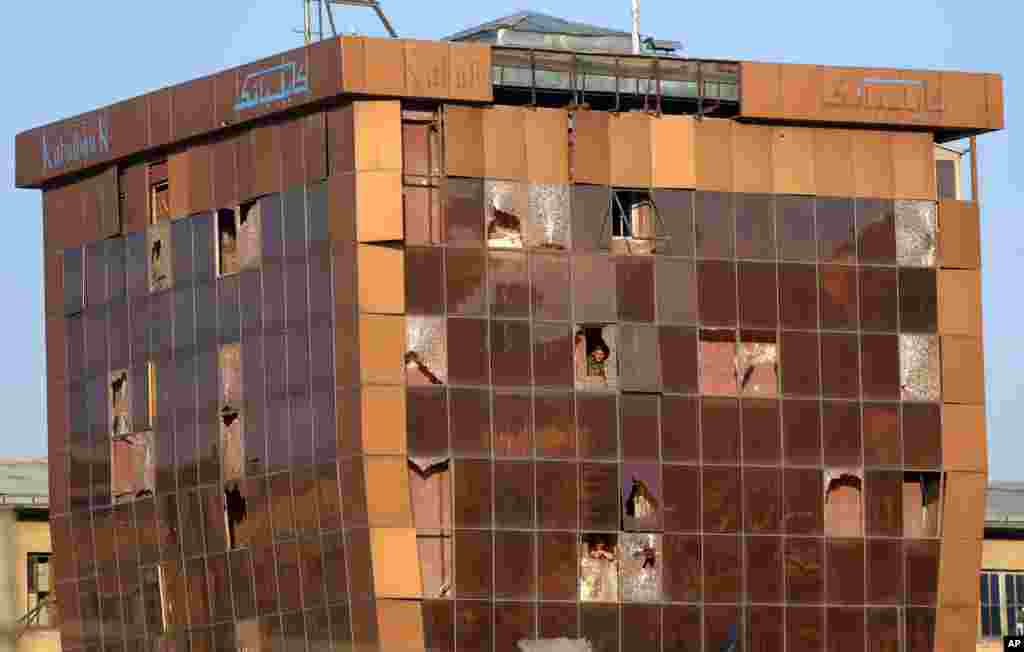 An Afghan security guard looks out of the window of Kabul Bank after a suicide car bombing attack in Kabul. A large suicide car bomb went off downtown, apparently targeting Justice Ministry employees and killing several people, an official said.