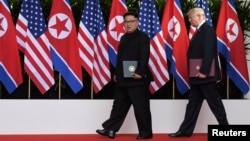 U.S. President Donald Trump and North Korea's leader Kim Jong Un walk off after signing documents during their summit at the Capella Hotel on Sentosa island in Singapore, June 12, 2018.