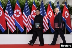 U.S. President Donald Trump and North Korea's leader Kim Jong Un walk during their summit at the Capella Hotel on Sentosa island in Singapore, June 12, 2018.
