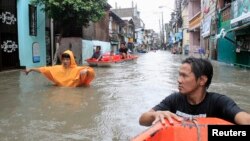 Residents wade through a flooded street during Tropical storm Fung-Wong in Pasay city, metro Manila, September 19, 2014.