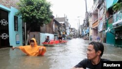 Warga berjalan melalui jalanan yang banjir akibat badai tropes Fung-Wong di wilayah Pasay, Manila (19/9).