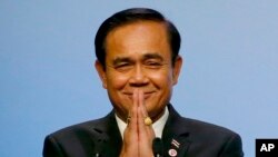 Thai Prime Minister Prayuth Chan-ocha gestures the Thai way shortly after accepting the ASEAN Summit and Related Summits' hosting and chairmanship for next year in Thailand from Singaporean Prime Minister Lee Hsien Loong, in Singapore, Nov. 15, 2018.