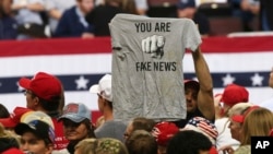 FILE - A Trump supporter holds a T-shirt reading "You Are Fake News" before a rally by President Donald Trump in Rochester, Minn., Oct. 4, 2018. Freedom House says that democracy in the U.S. weakened significantly and blames U.S. President Donald Trump.