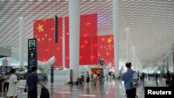 Pelancong berjalan melewati bendera Tiongkok jelang libur Hari Nasional dan Pekan Emas Tiongkok, di Bandara Internasional Baoan Shenzhen di Shenzhen, Provinsi Guangdong, Tiongkok 30 September 2021. (Foto: REUTERS/Aly Song)