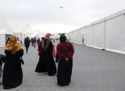 FILE - Afghan refugees walk alongside temporary housing in Liberty Village on Joint Base McGuire-Dix- Lakehurst in Trenton, New Jersey, Dec. 2, 2021.