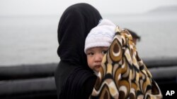 Une femme afghane et son enfant à leur arrivée de Turquie sur les rives de l'île grecque de Lesbos sur un canot gonflable, le 23 septembre 2015.