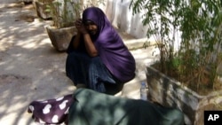 Asha and Muna wait for assistance outside the UNHCR office in Galkayo town. Muna , is sleeping on the floor because she could not withstand the pain in her thigh. She was stabbed by a rapist on Nov. 26 2010.