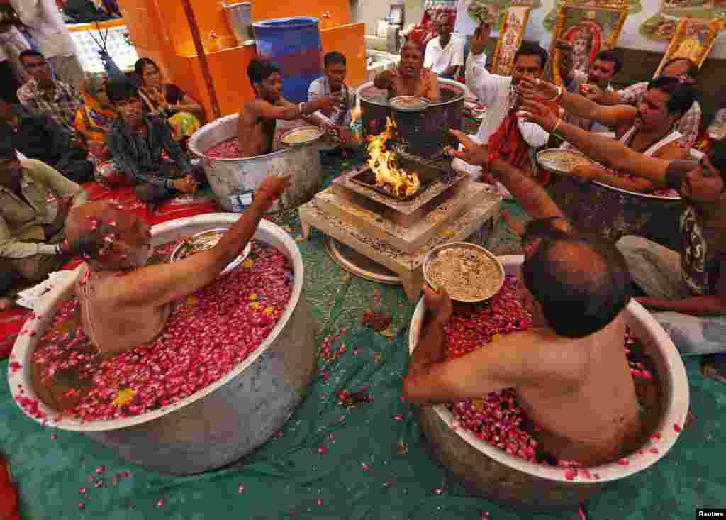 Hindu priests sit in cauldrons of water and rose petals as they perform the &quot;Parjanya Varun Yagam&quot;, a special prayer for rain, in the western Indian city of Ahmedabad.