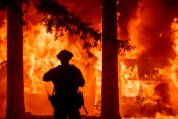 Firefighters try to get control of the scene as a wildfire burns many homes in the Indian Falls neighborhood of Plumas County, California on July 24, 2021. (AFP Photo)