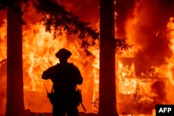 Firefighters try to get control of the scene as a wildfire burns many homes in the Indian Falls neighborhood of Plumas County, California on July 24, 2021. (AFP Photo)