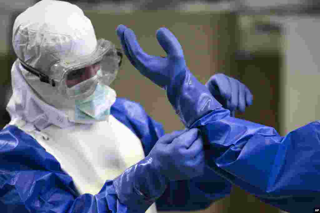 A volunteer of the German forces Bundeswehr helps to fix a glove of a protective suit during a training for the Ebola virus in Appen about 25 kilometers (15,5 miles) north of Hamburg, Germany. 