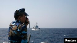 An officer of the Vietnamese coast guard officer speaks on a radio as he monitors a Chinese vessel (top) in the South China Sea during a period of tension in 2014.