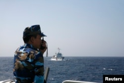 FILE - An officer of the Vietnamese coast guard officer speaks on a radio as he monitors a Chinese vessel (top) in the South China Sea, about 210 km (130 miles) off Vietnam's shore May 15, 2014.