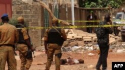 Des éléments forces de sécurité burkinabè se tiennent près du corps d'un suspect jihadiste abattu à Ouagadougou, le 22 mai 2018.