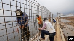 FILE - Workers build a wall which will be used as a barrier to prevent sea water from flowing onto land and cause flooding in Jakarta, Indonesia, Dec. 8, 2015. 