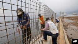 FILE - Workers build a wall which will be used as a barrier to prevent sea water from flowing onto land and cause flooding in Jakarta, Indonesia, Dec. 8, 2015. 