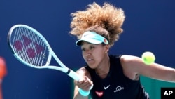 FILE - Naomi Osaka, of Japan, returns to Maria Sakkari, of Greece, during the quarterfinals of the Miami Open tennis tournament in Miami Gardens, Florida, March 31, 2021. 