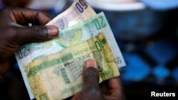 A man holds several Gambian banknotes at Serrekunda market in Banjul, Gambia, Jan 27, 2017.